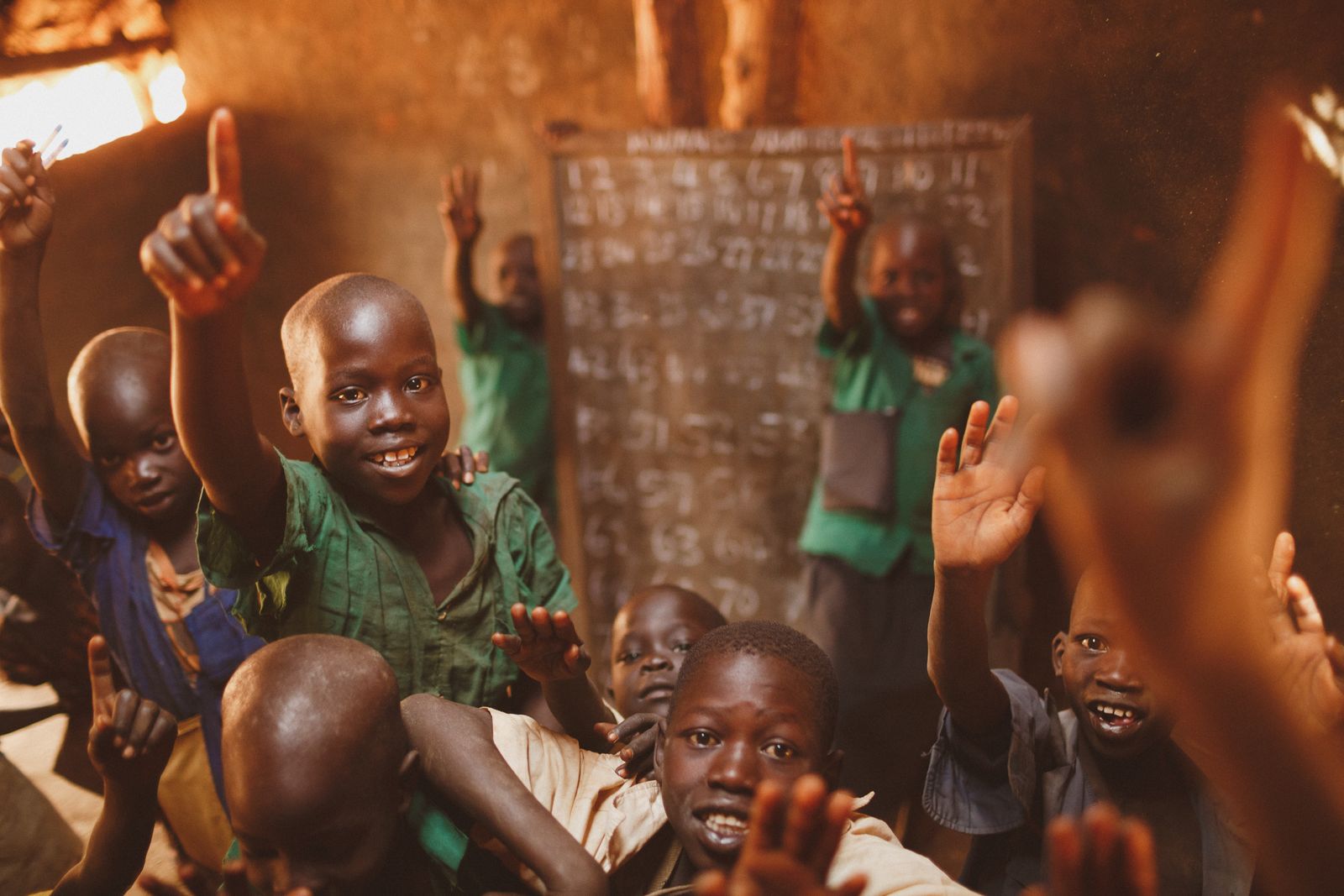 Smiling boys raising their hands in a classroom