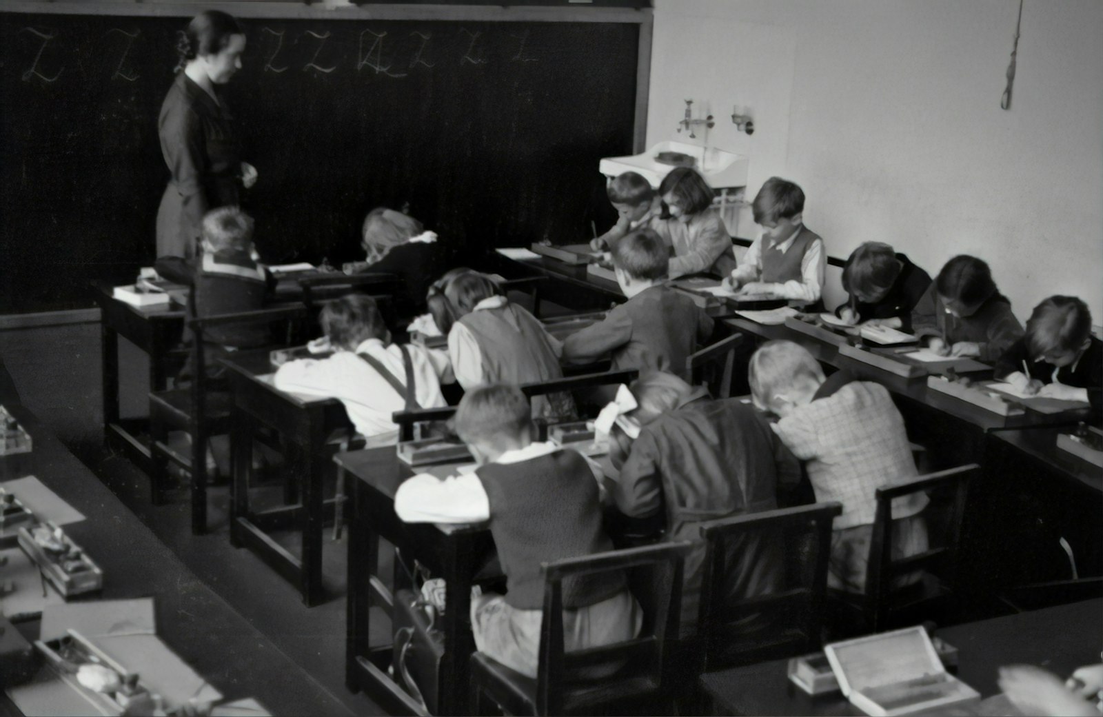A teacher helping young students with an exercise in a bright classroom