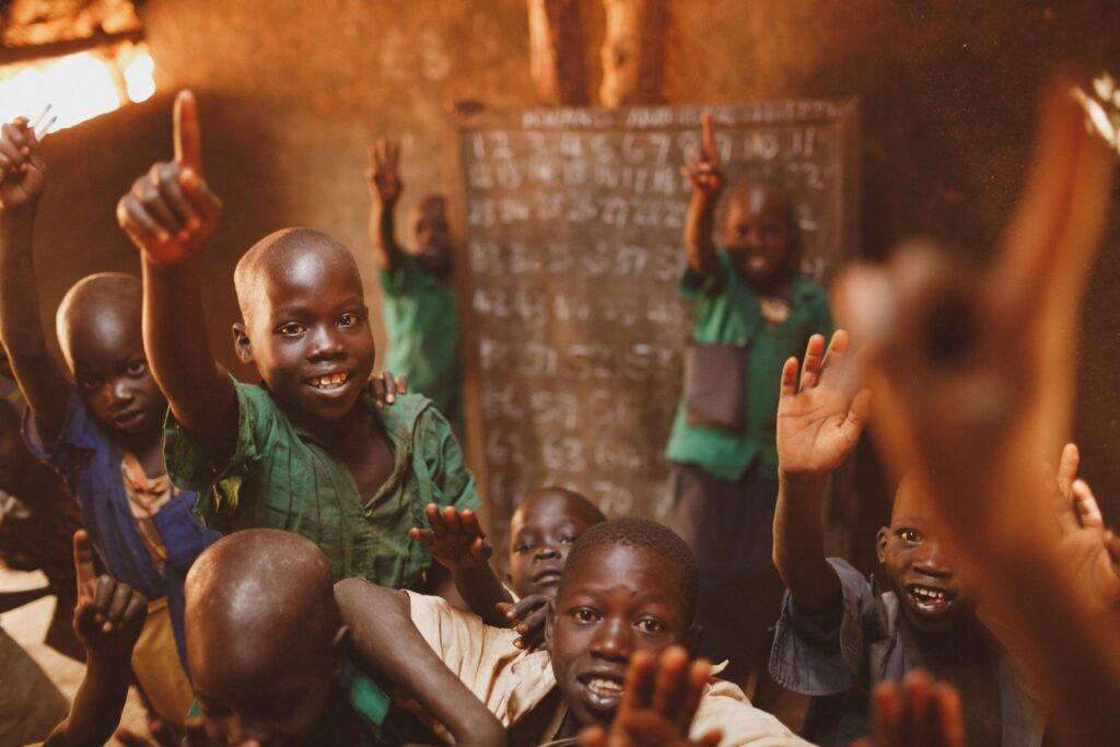 Smiling boys raising their hands in a classroom