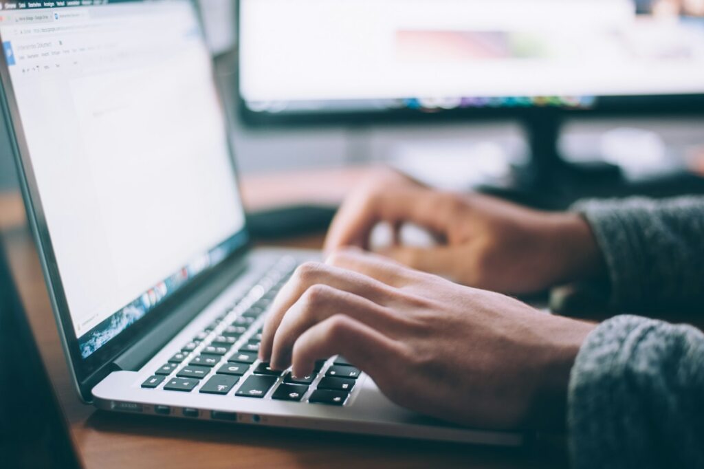 Person typing on a MacBook Pro laptop, representing website and CMS support work