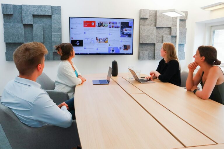 A team in a meeting room looking at a website on a large wall screen